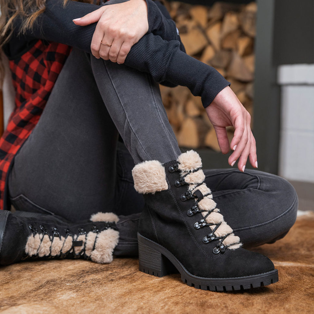 Woman wearing lace-up high heel fashion hiker boots by a fire