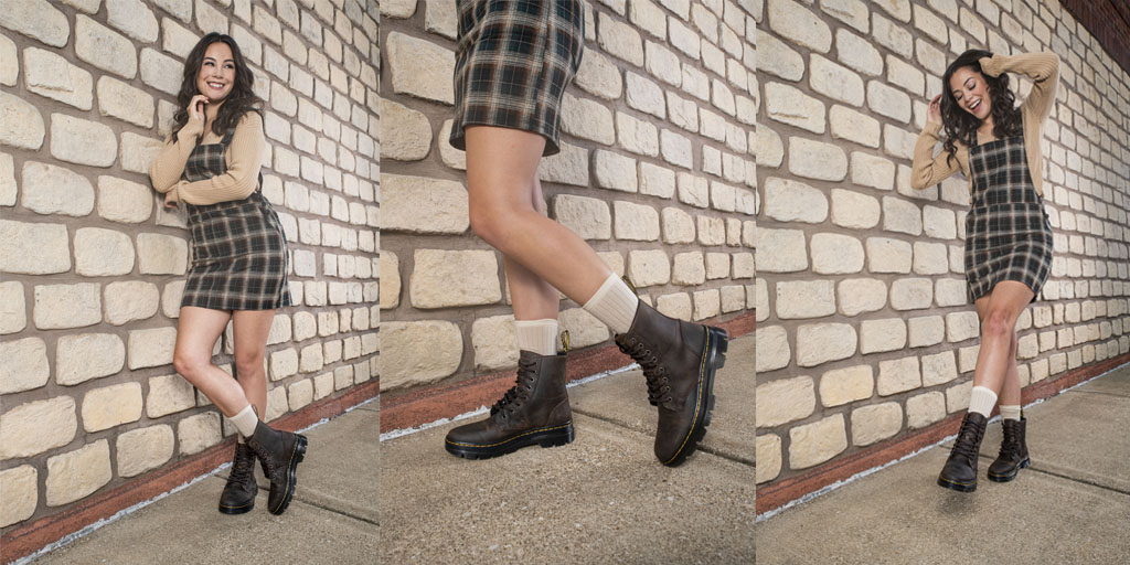 Bring on the apple cider with this fun fall look. Model is wearing a plaid overalls mini dress with a nude sweater, brown combat boots, and visible cream socks.